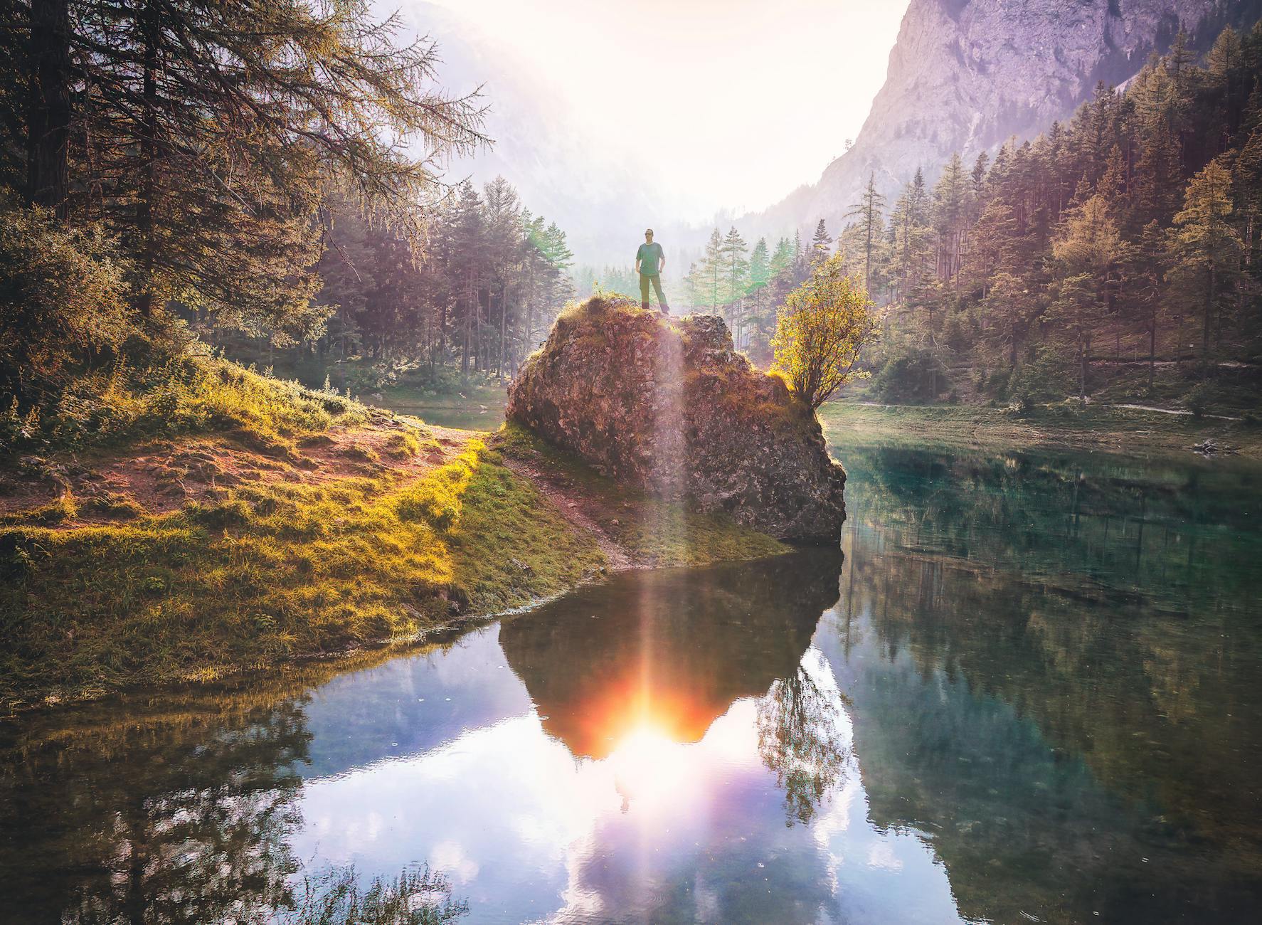 photo of person standing on rock near lake