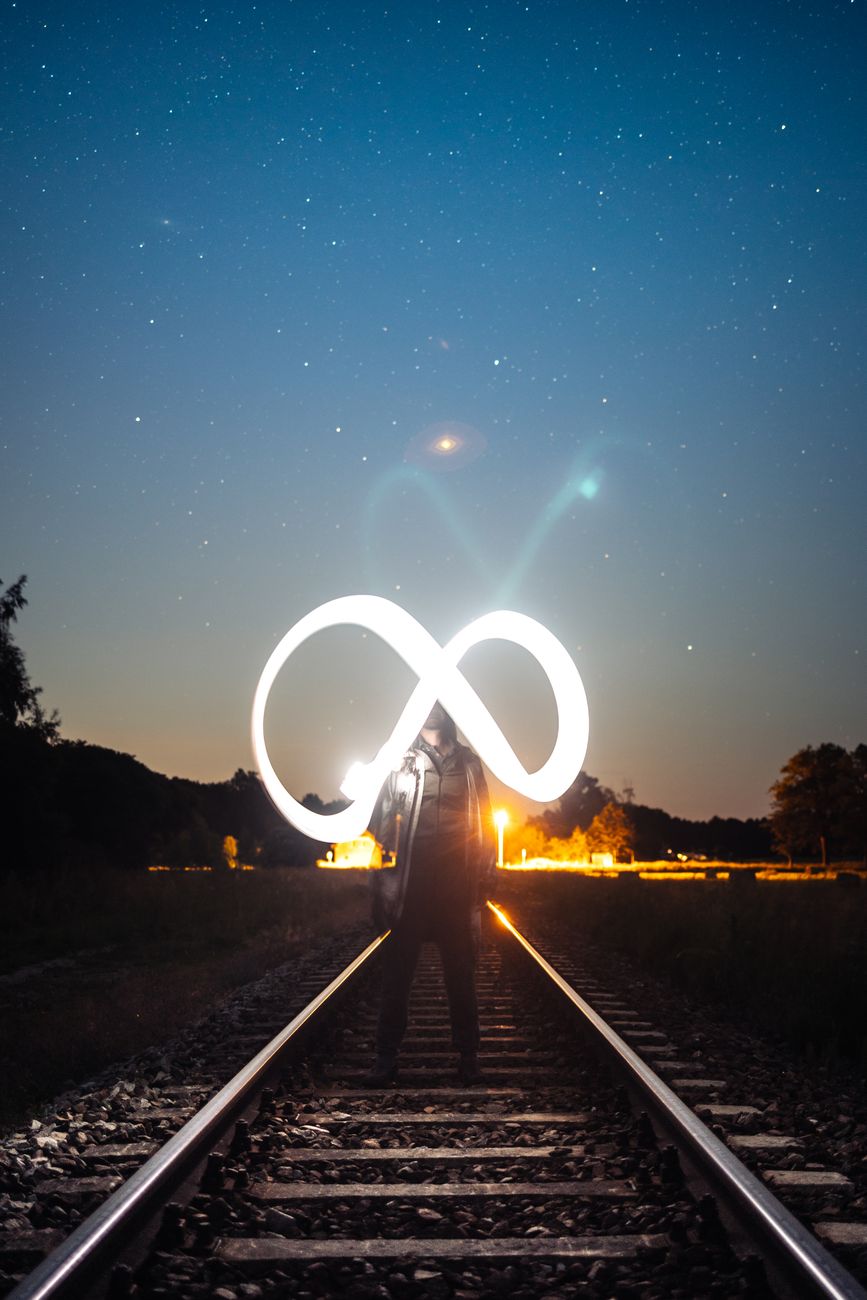 infinity symbol over man standing on railway tracks