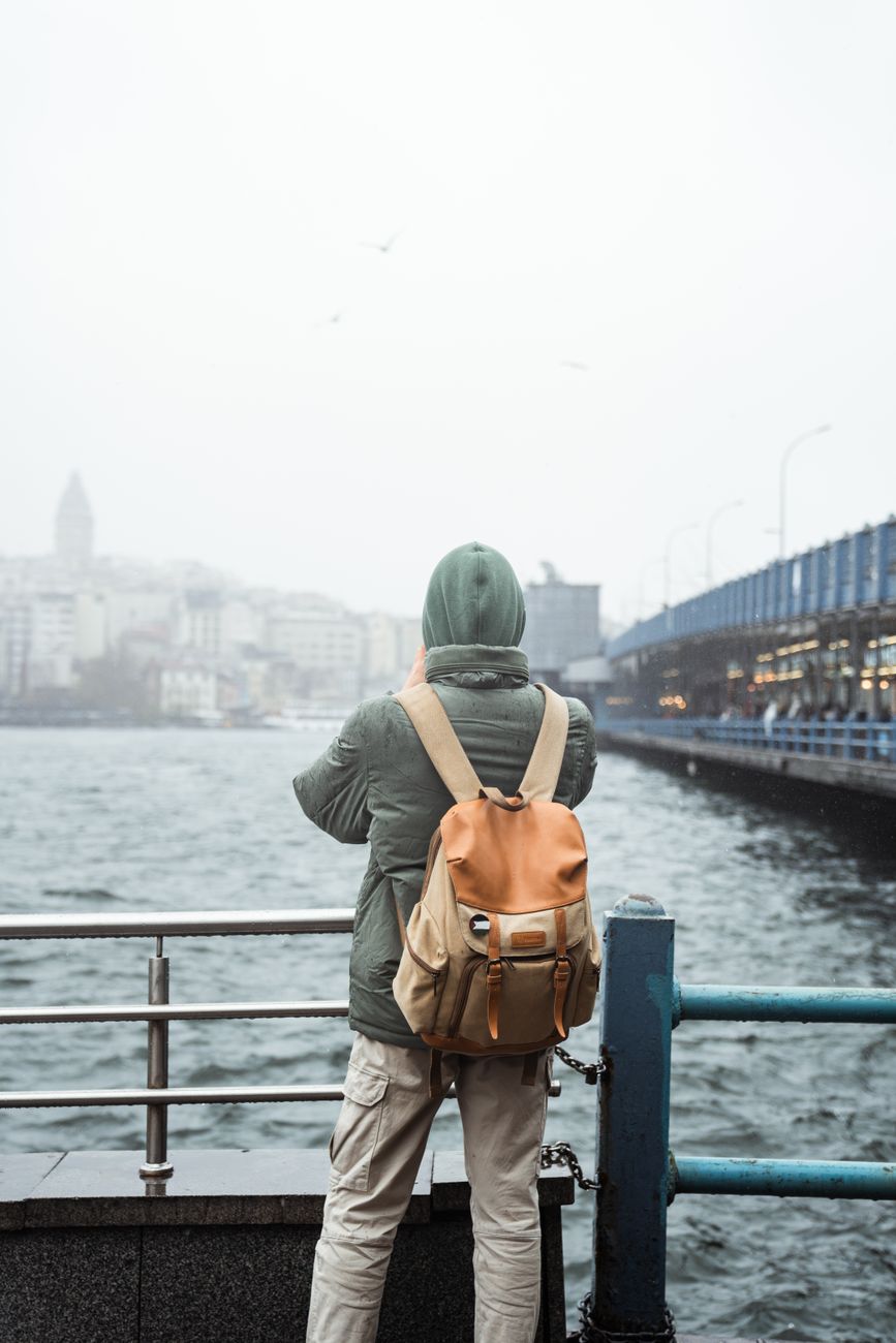 person in jacket with backpack looking at bay