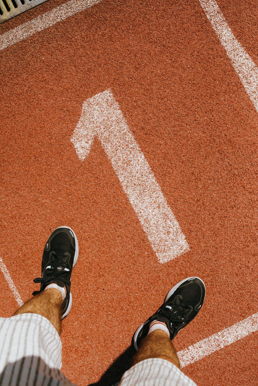 man standing on a running track on place with number one sign